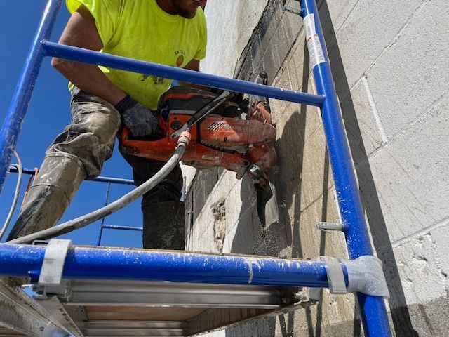 A man is using a chainsaw to cut a hole in a wall.