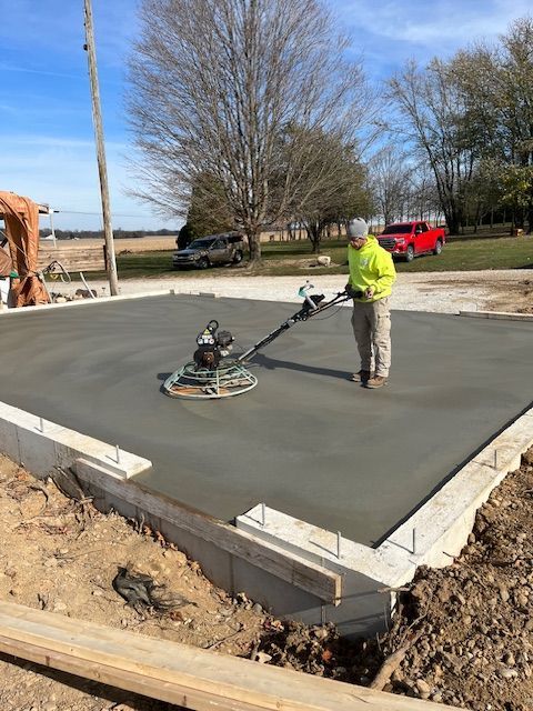 A man is using a machine to smooth concrete on a construction site.