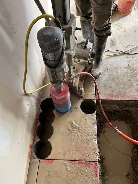 A person is using a machine to cut holes in a concrete wall.