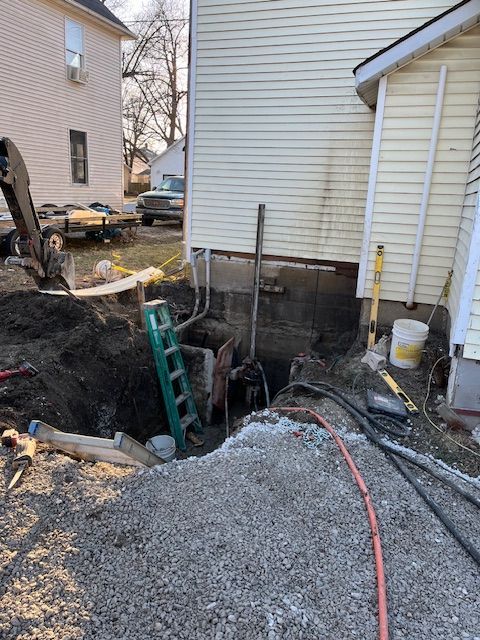 A ladder is sitting in the dirt in front of a house.