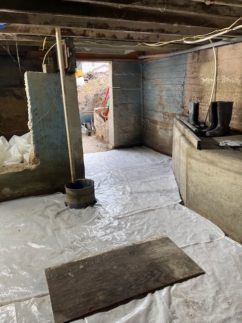 A basement with a white tarp on the floor.