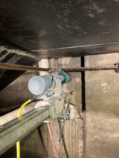 A close up of a pipe in a room with a hose attached to it.