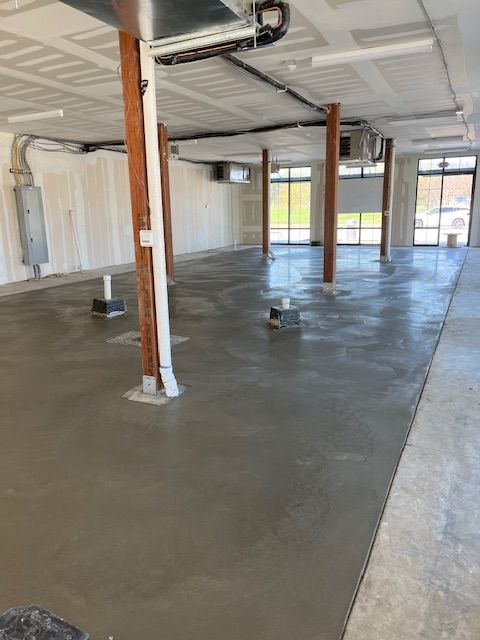 A large empty room with a concrete floor and wooden pillars.