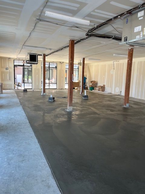 A large empty room with a concrete floor and pillars.