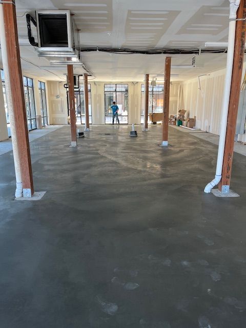 A man is standing in a large empty room with a concrete floor.