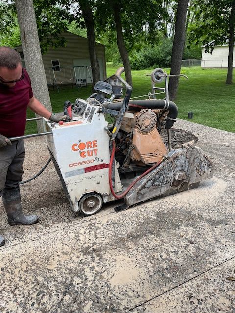 A man is using a core cut concrete saw to cut a concrete patio.