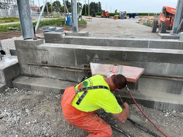 A man in a yellow shirt is working on a concrete wall.