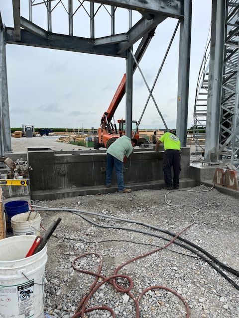 Two construction workers are working on a concrete structure