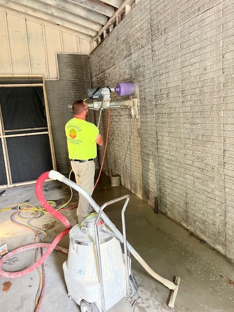 A man is using a machine to cut a hole in a brick wall.