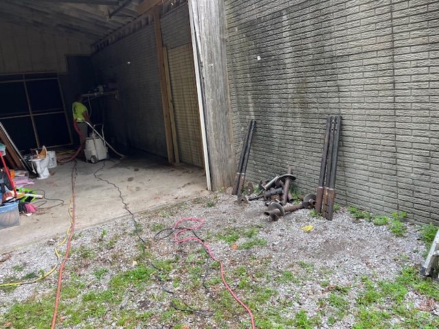 A man is cleaning a brick wall with a vacuum cleaner.