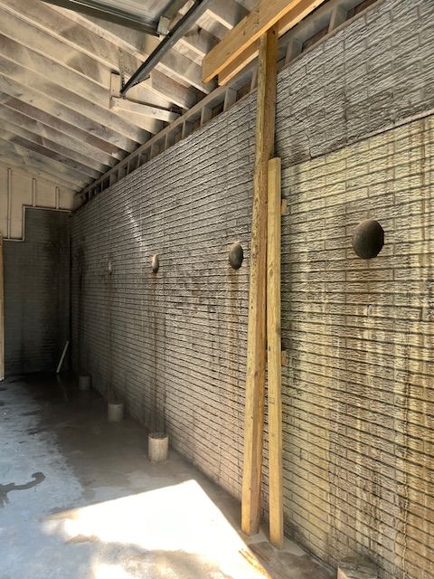 A brick wall with a wooden post in the middle of it