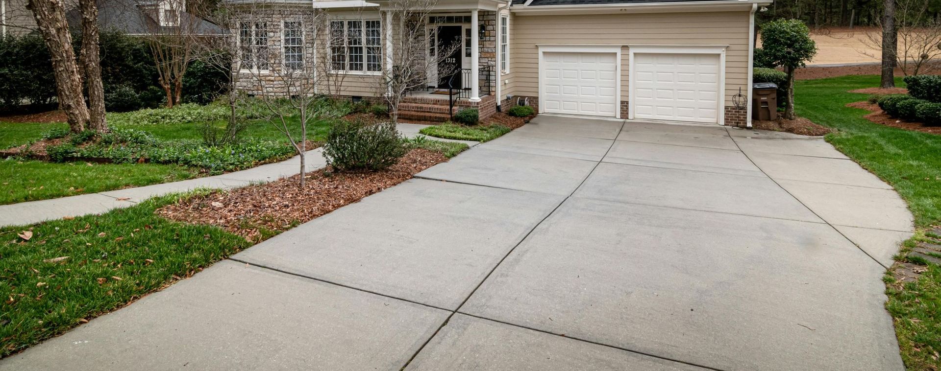 A concrete driveway leading to a house with two garages.