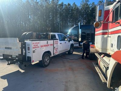 A man is changing a tire on a truck in a parking lot.
