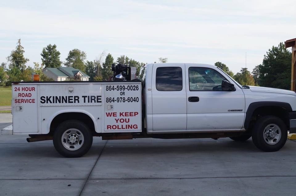 A white skinner tire truck is parked on the side of the road