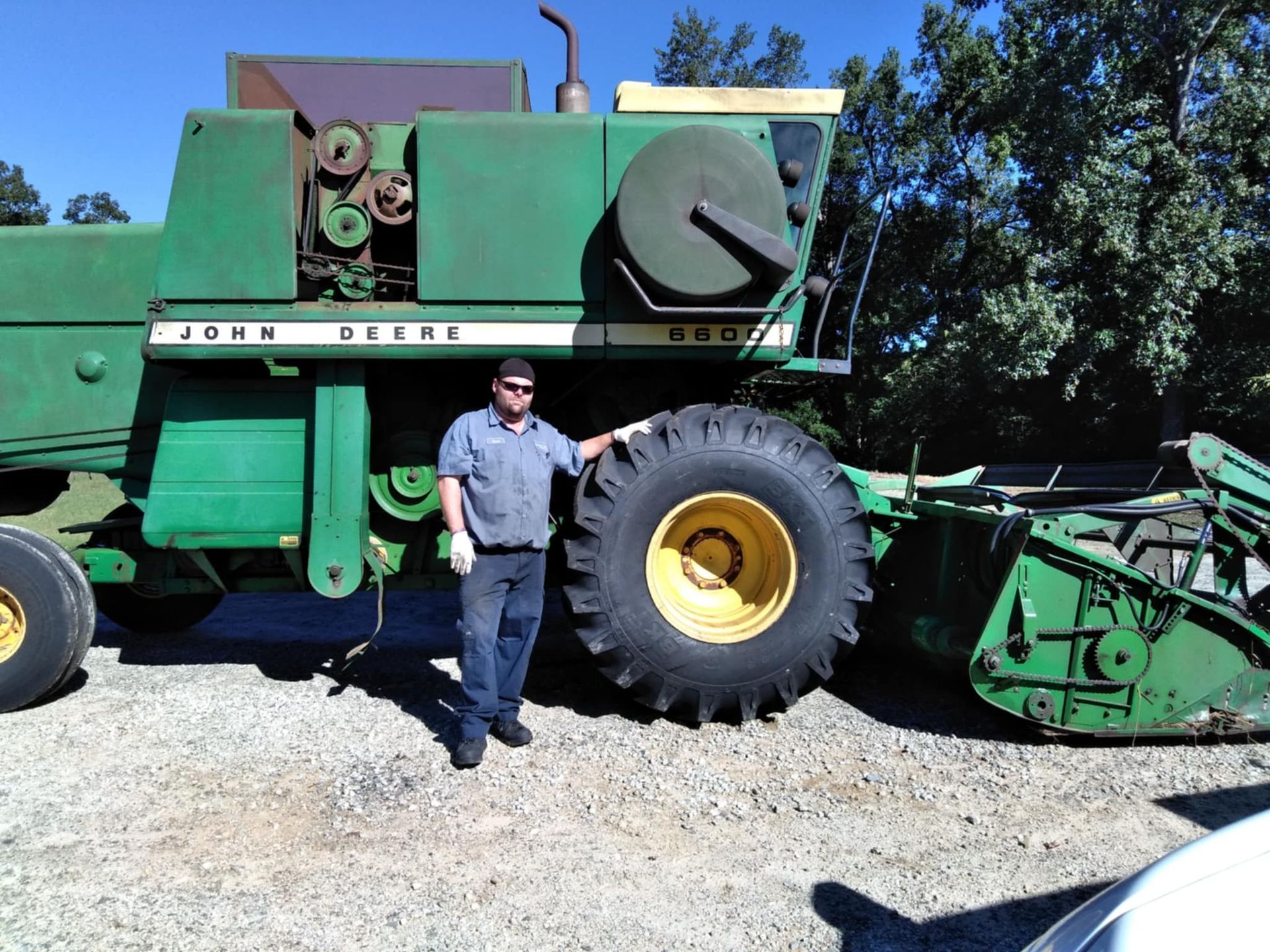 A man standing next to a john deere combine harvester