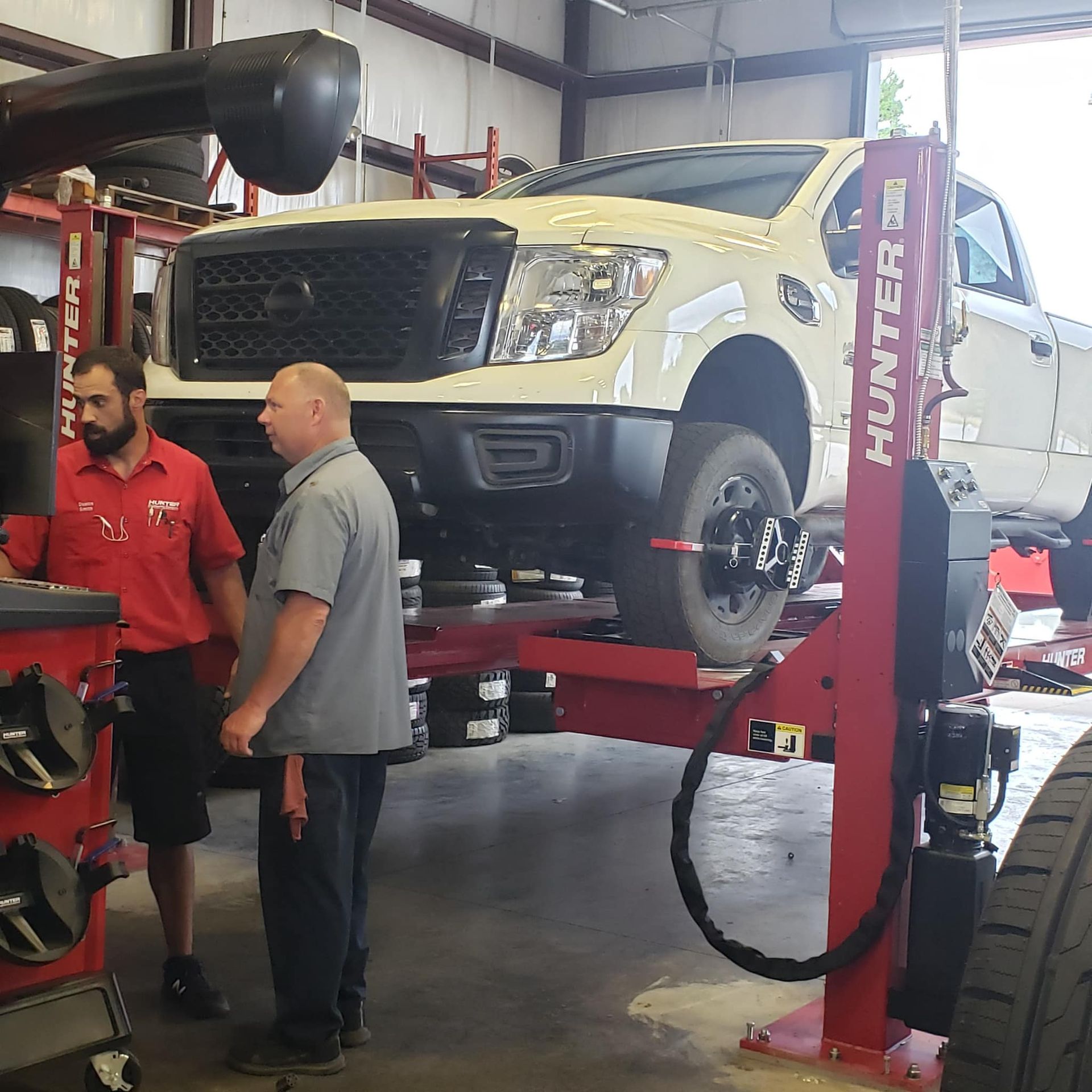 A white truck is on a hunter lift in a garage
