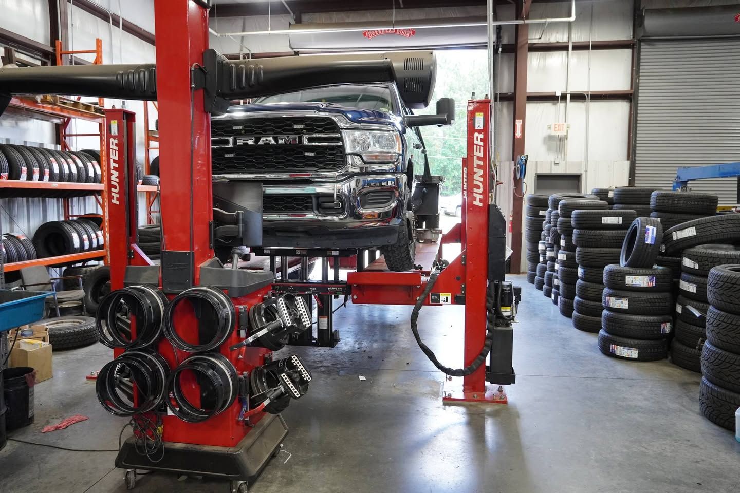 A truck is sitting on a lift in a tire shop.
