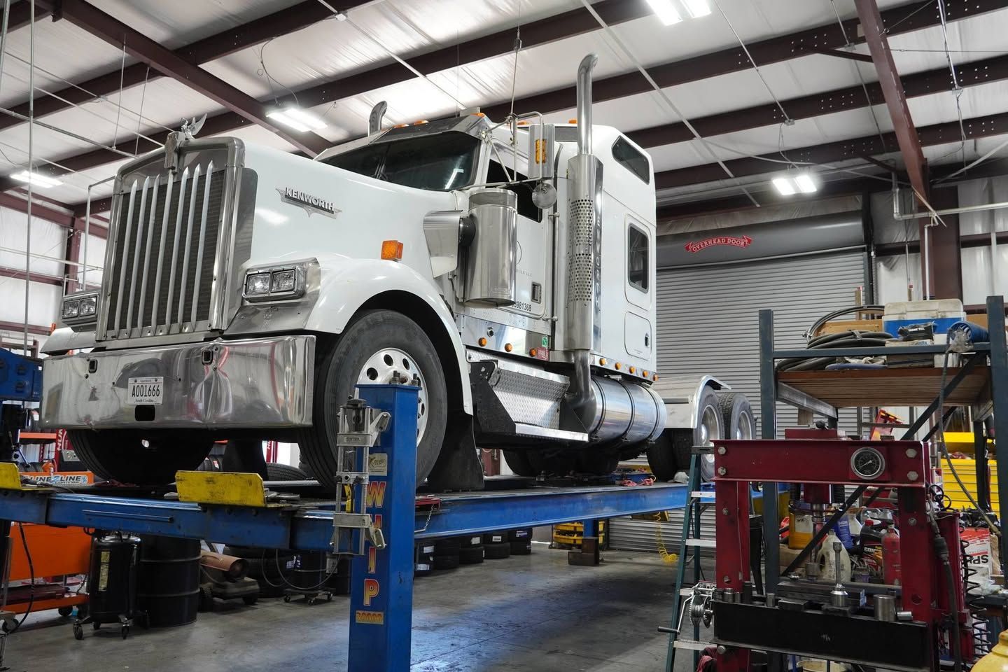 A semi truck is sitting on a lift in a garage.