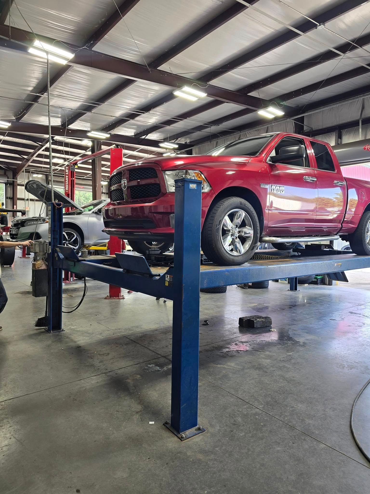 A red truck is sitting on a lift in a garage.