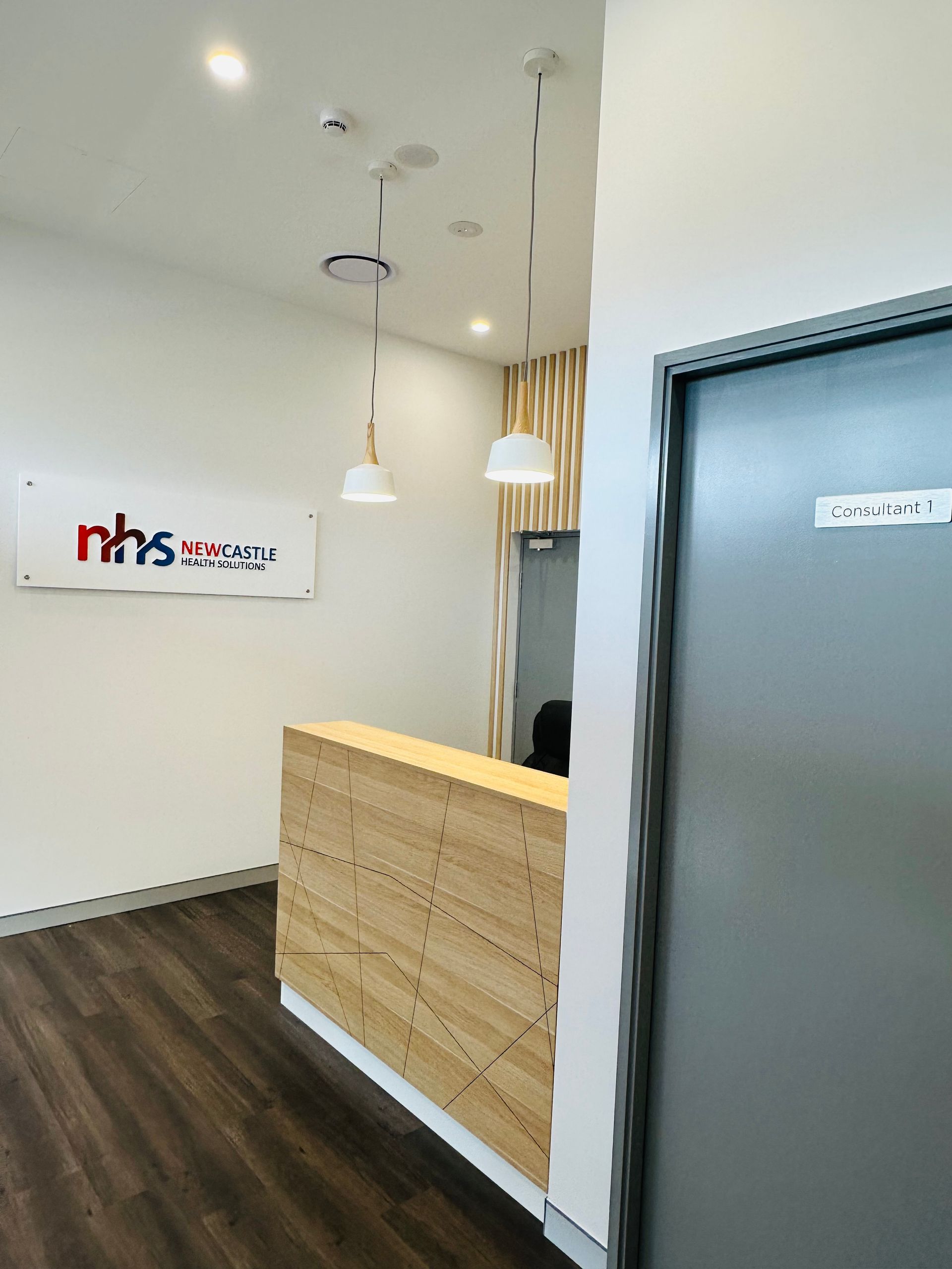 A Reception Area With A Wooden Counter And A Sign That Says NHS On It — Nyon Shopfitters in Morisset, NSW