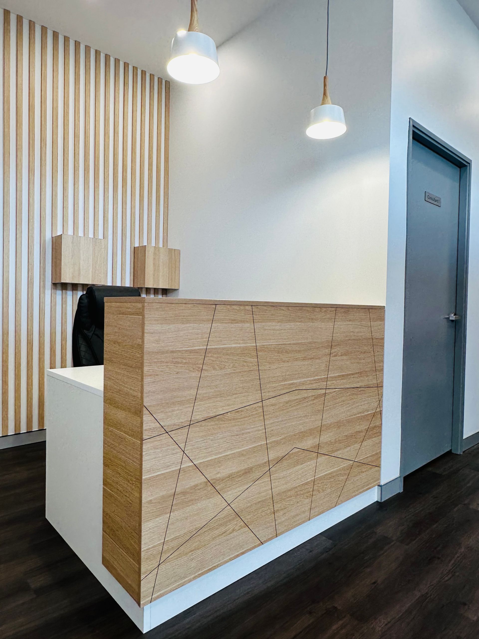 A Wooden Reception Desk In A Room With A Door — Nyon Shopfitters in Morisset, NSW