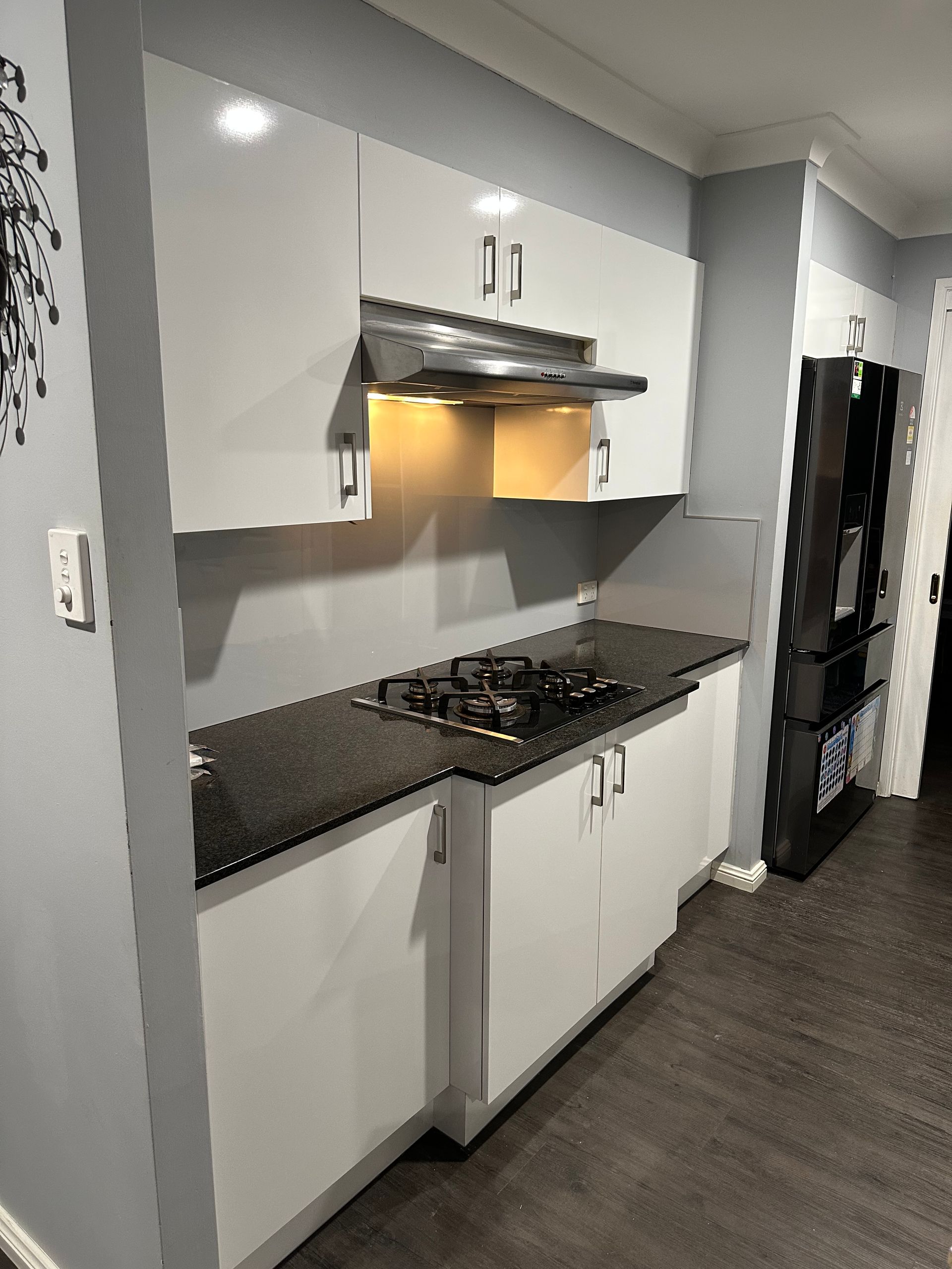 A Kitchen With White Cabinets And A Black Counter — Nyon Shopfitters in Morisset, NSW