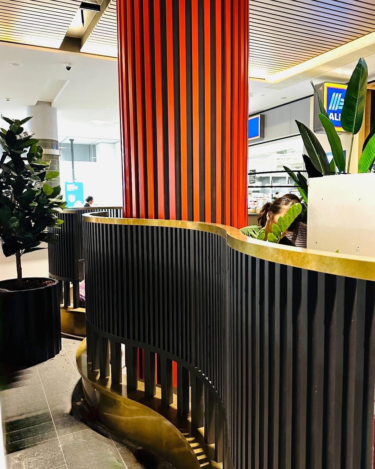 A Woman Is Sitting At A Table In A Restaurant With A Curvy Divider — Nyon Shopfitters in Morisset, NSW