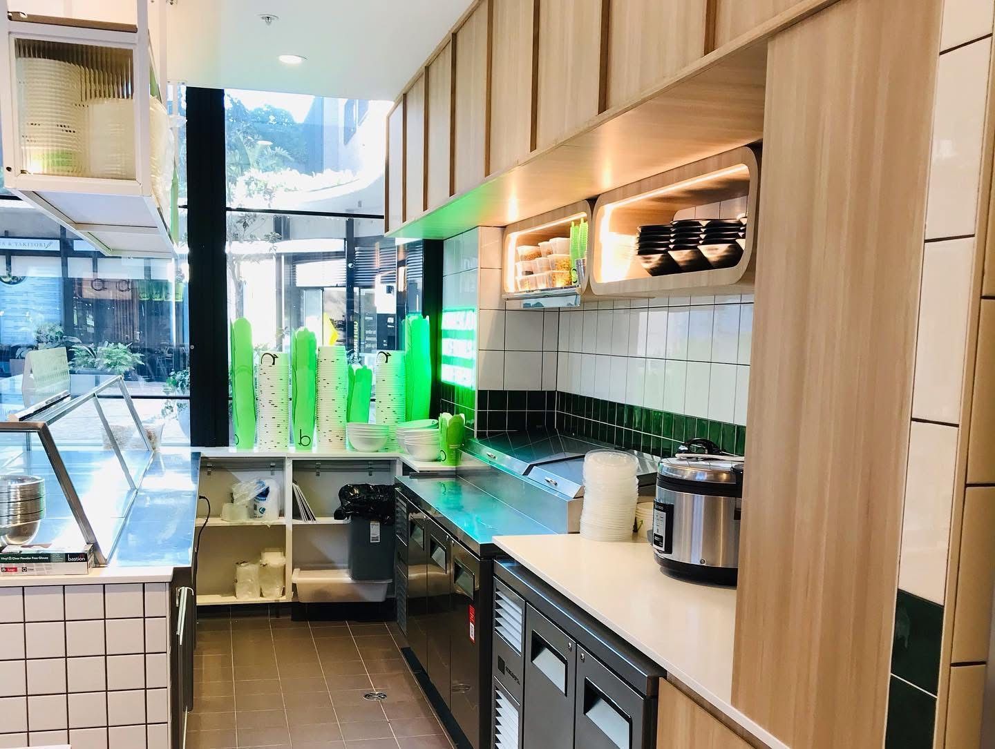 A Kitchen In A Restaurant With Wooden Cabinets — Nyon Shopfitters in Morisset, NSW