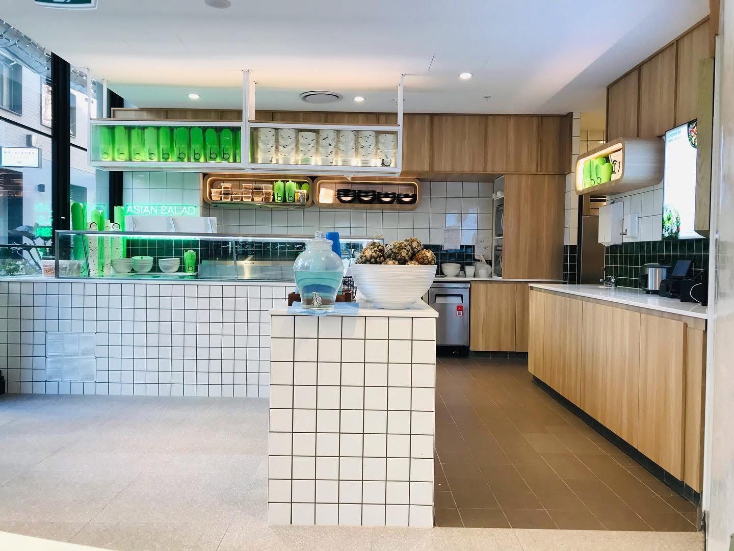 A White Kitchen With Wooden Cabinets — Nyon Shopfitters in Morisset, NSW