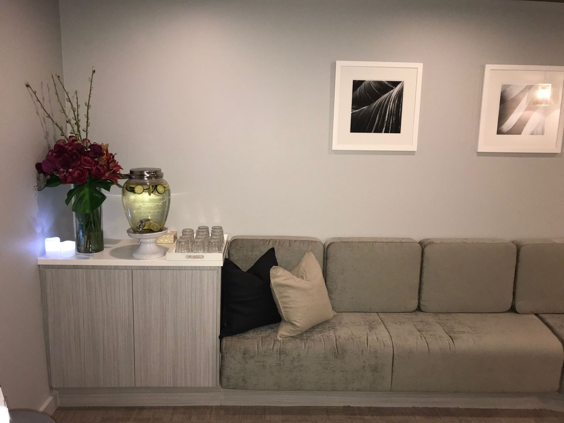 A living room with a couch and a vase of flowers on the wall.
