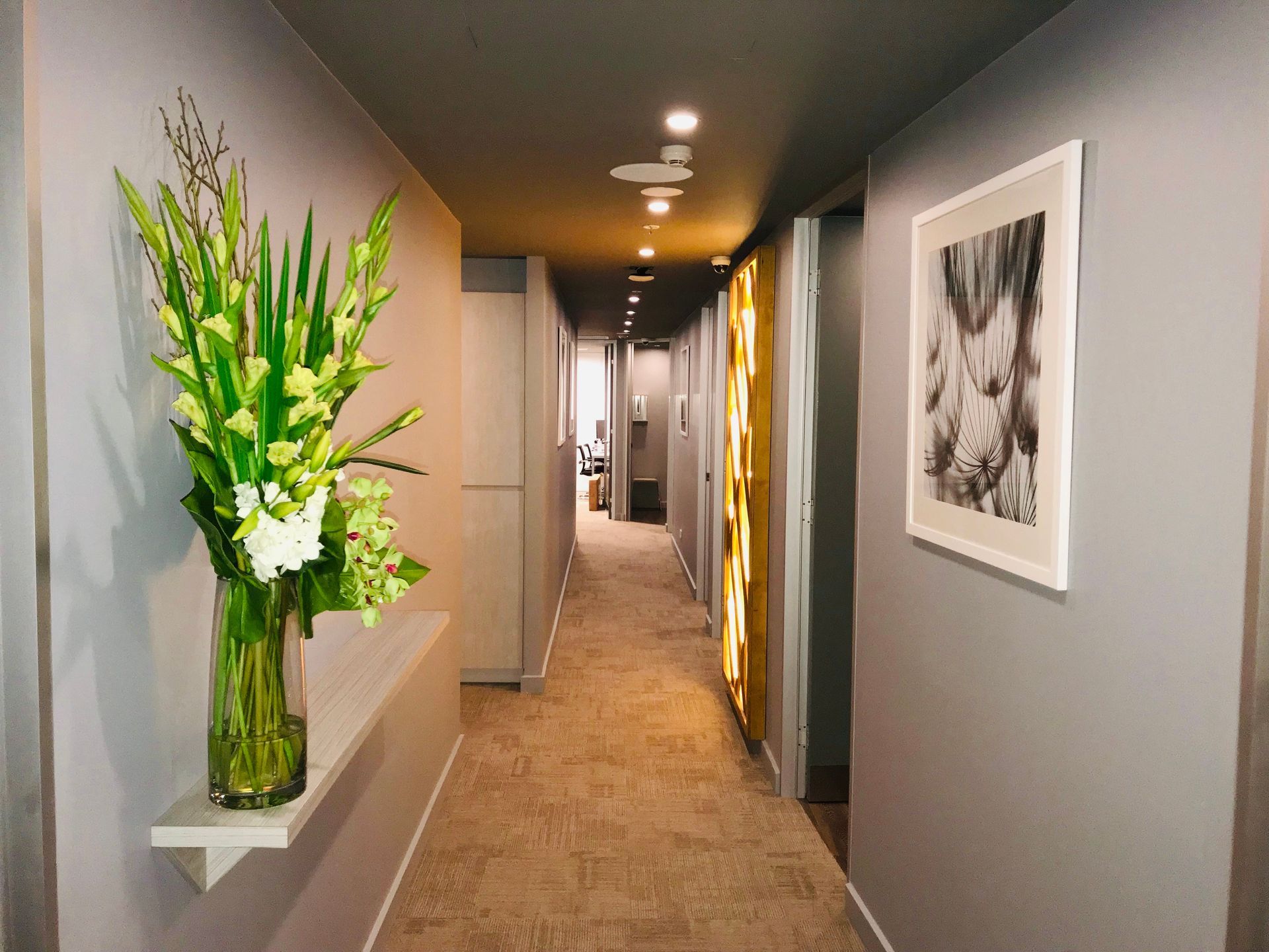 A long hallway with a vase of flowers on a shelf.