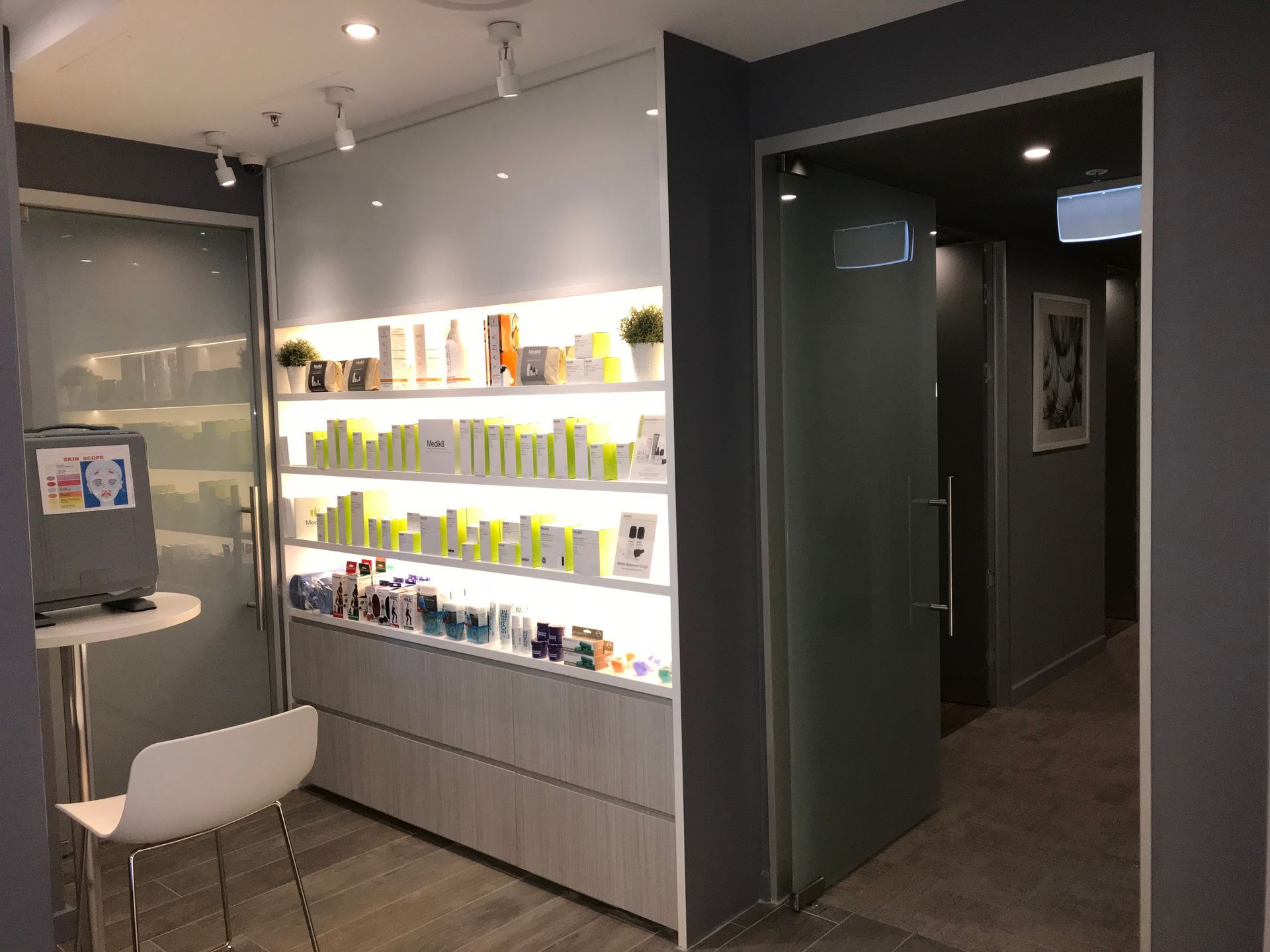 A room with a shelf full of cosmetics and a chair.