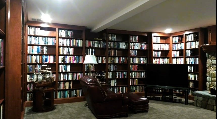 Cozy basement library with neatly organized books and warm lighting.