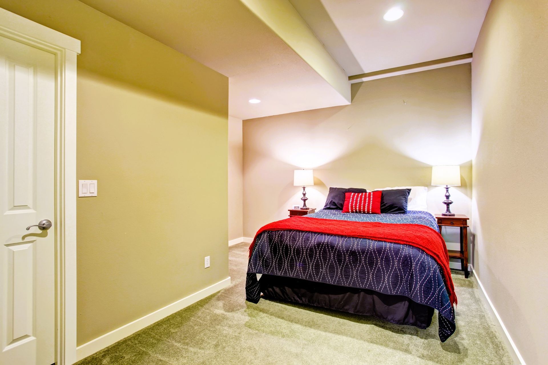 Cozy bedroom with a red and black bedspread, side tables, and lamps.