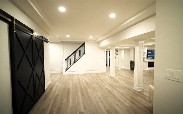 Finished basement with wood floors, barn door, and staircase
