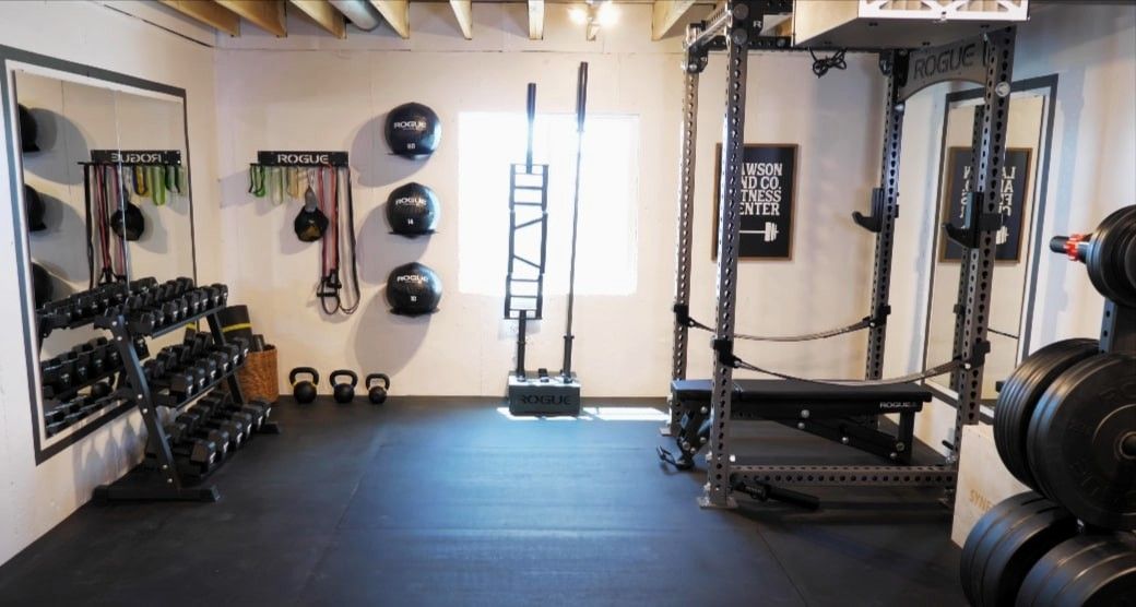 Basement home gym with dumbbell rack, medicine balls, and squat rack.