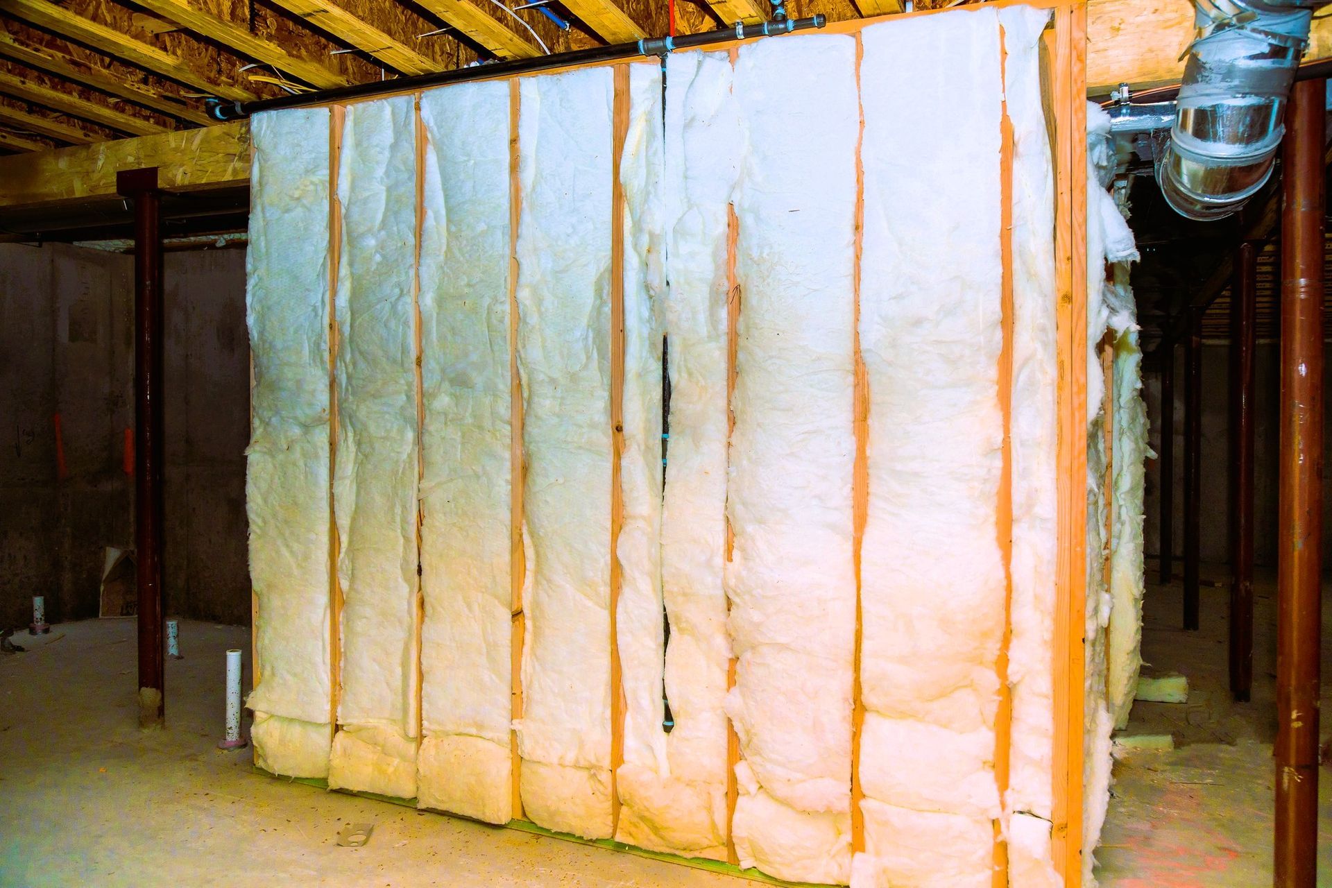 Insulation material installed between wooden studs in unfinished basement.