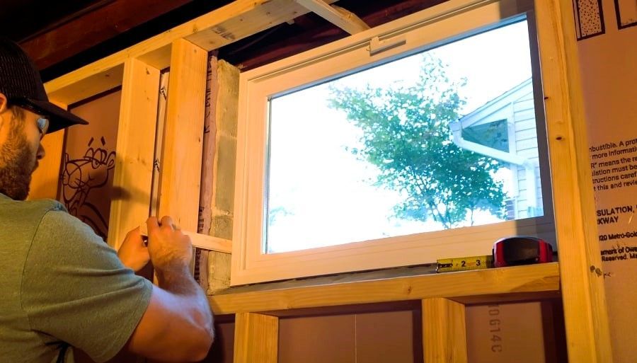 Measuring wooden frame for basement window installation