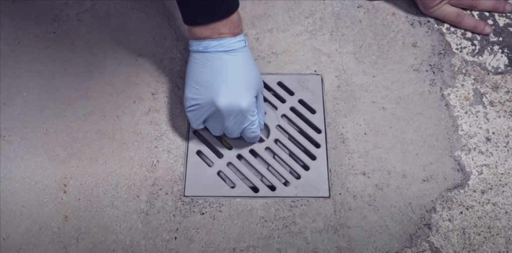 Experienced professional installing a new basement floor drain in Grand Rapids, Michigan.