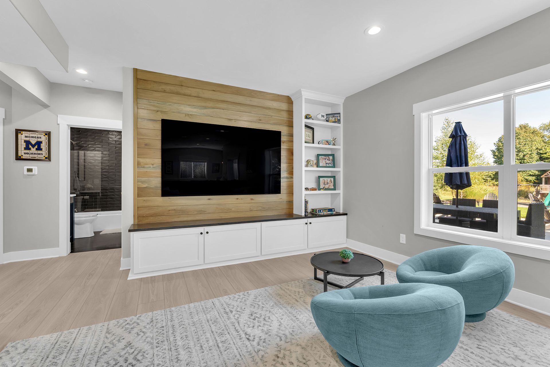 A family room with two chairs , a table , and a flat screen tv.