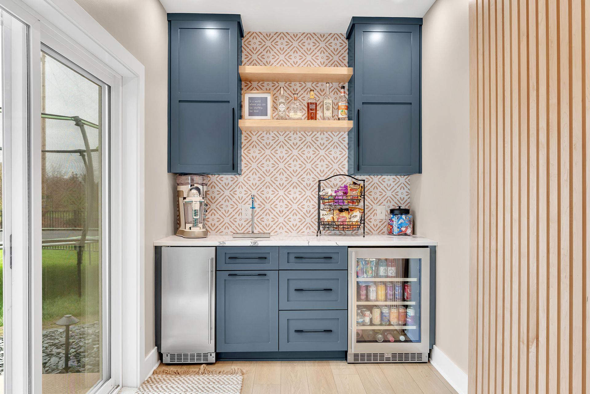 A wet bar with blue cabinets and a sliding glass door