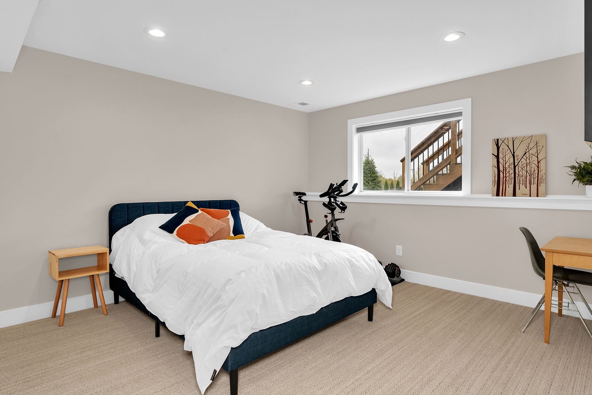 A bedroom with a bed , desk , chair and exercise bike.