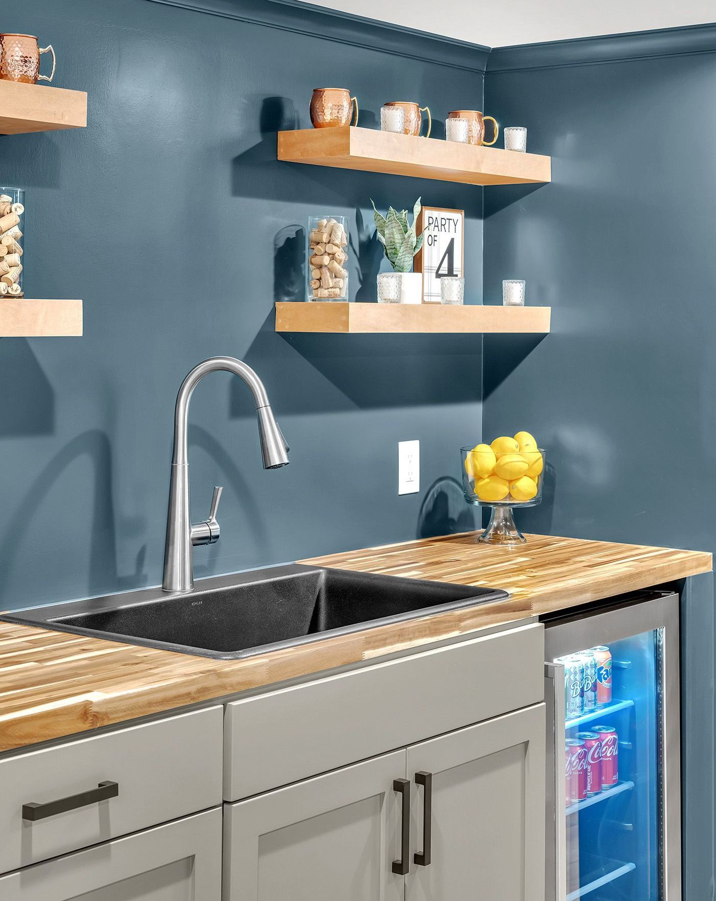 A kitchen with a sink a refrigerator and shelves