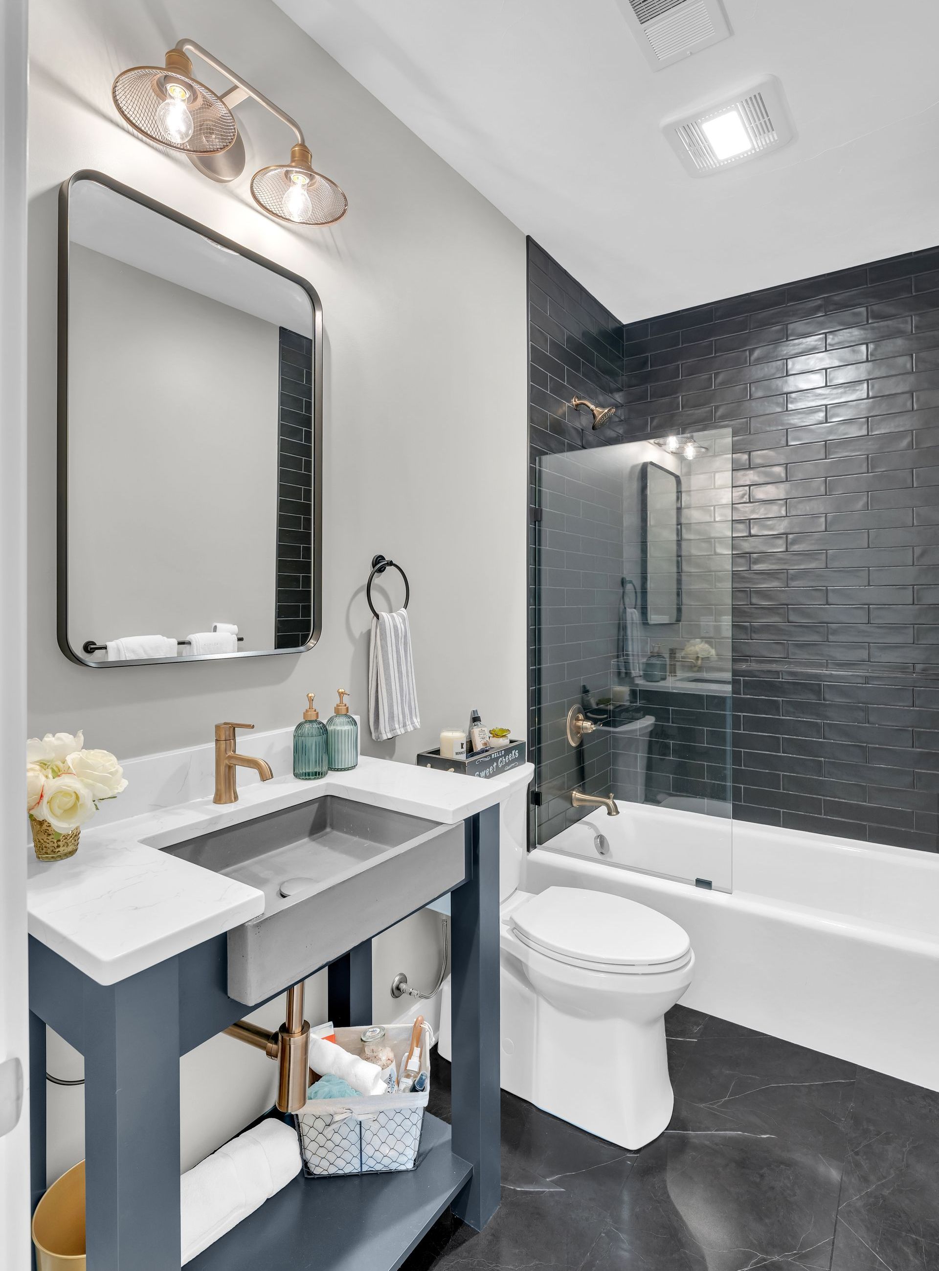 A modern bathroom with a sink , toilet , bathtub and mirror.