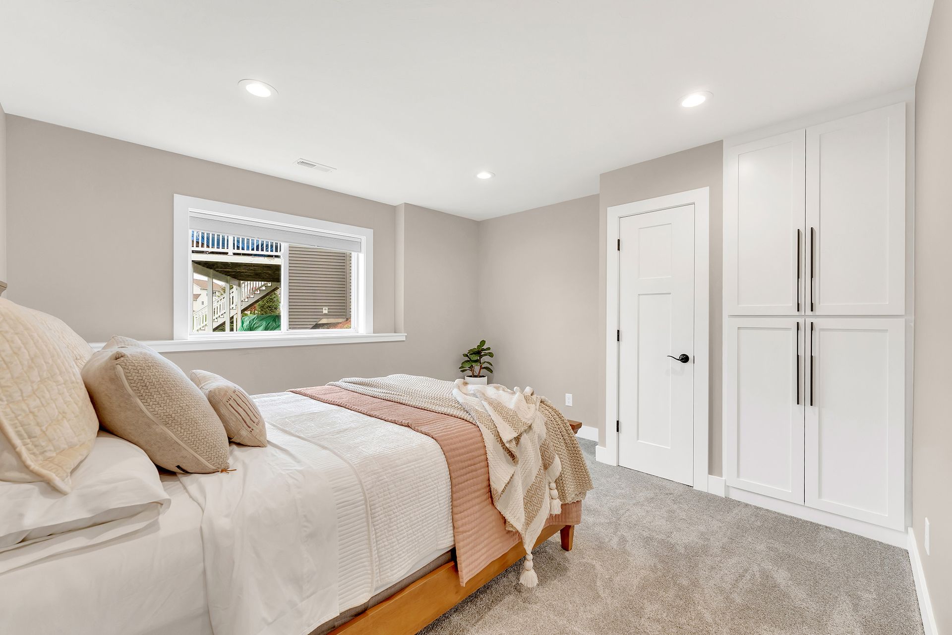 A bedroom with a bed , cabinets , and a window.