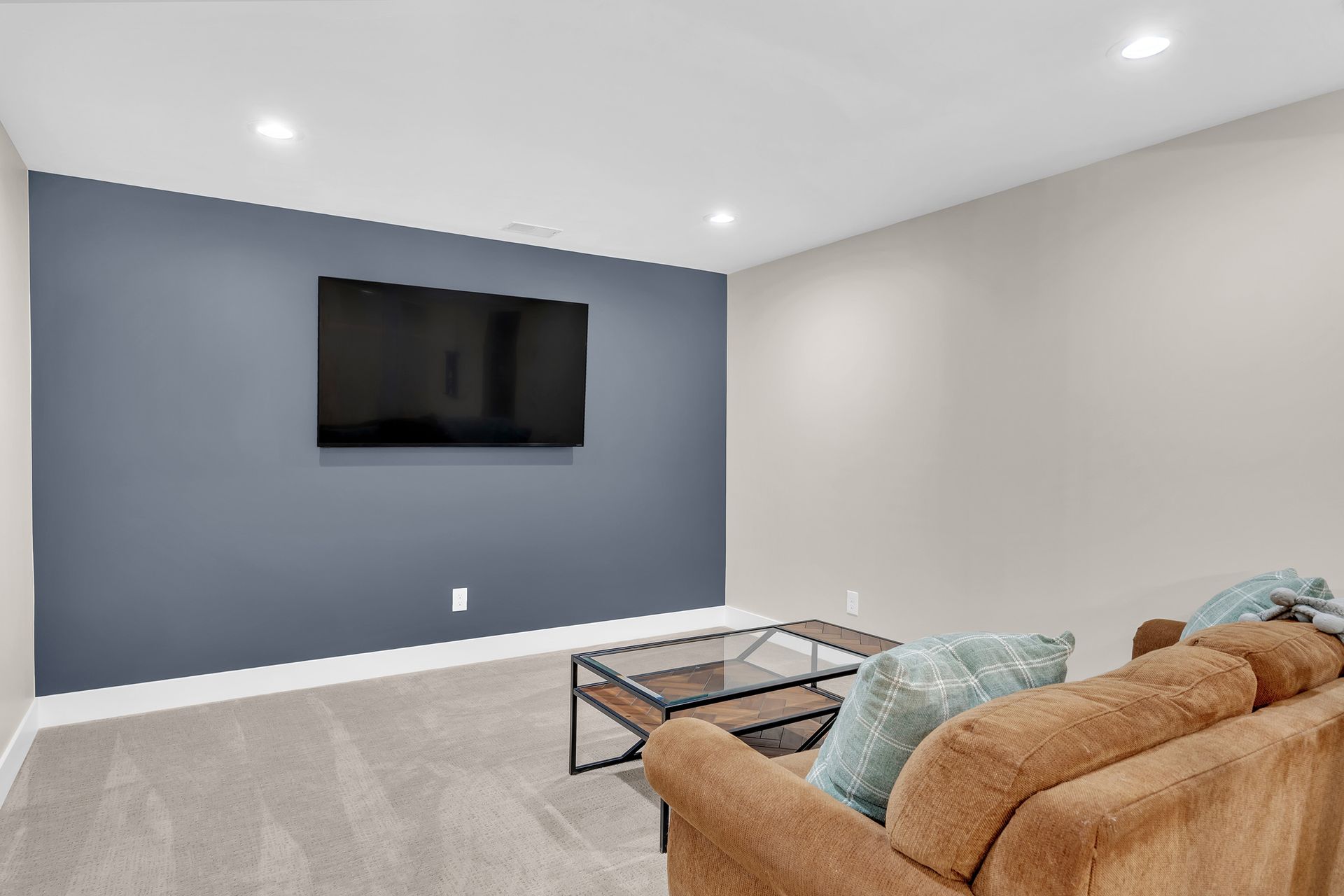 A living room with a couch and a flat screen tv on the wall.