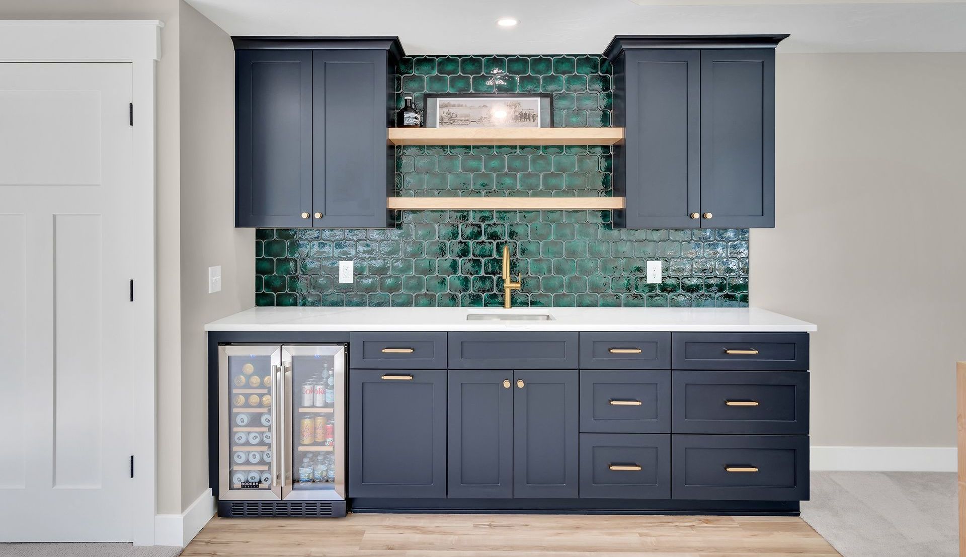 A wet bar with blue cabinets , a sink , and a refrigerator.