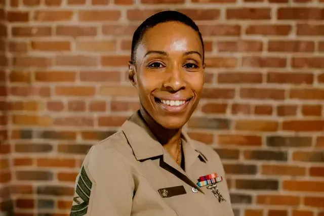 Portrait of a military woman in uniform smiling in front of the brick wall background