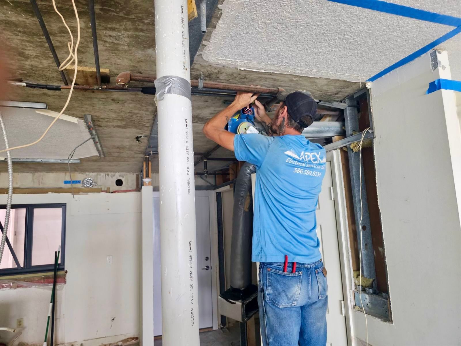 A man in a blue shirt is working on a pipe in a room.