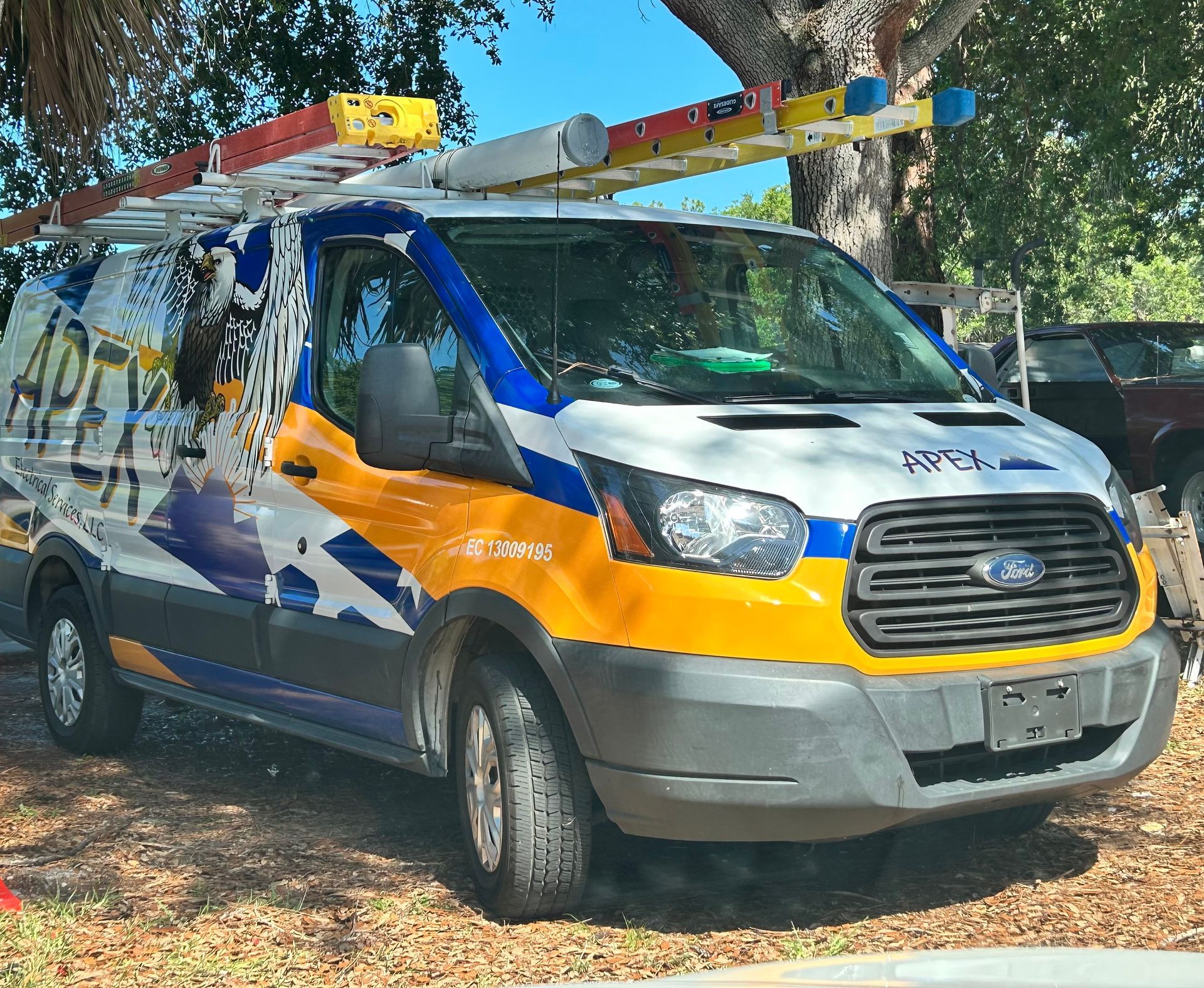 A yellow and blue van with a ladder on top of it